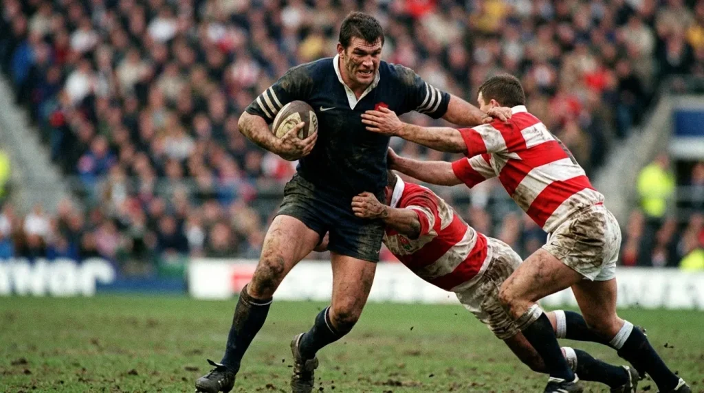 French rugby forward charging into English defenders during a Champions Cup match